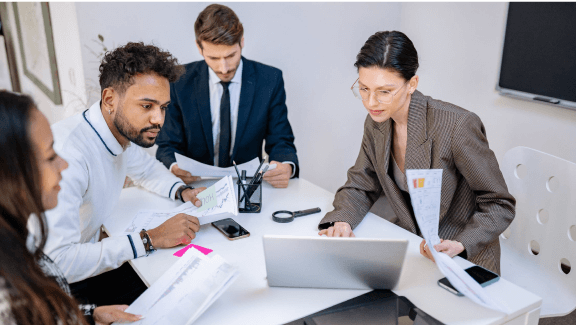 Photograph of 4 people in an office using a laptop to make a company presentation