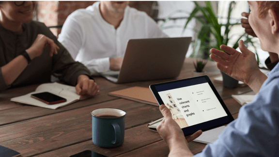 Photograph of 3 people gathered together talking about a report with a tablet