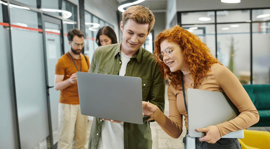 A woman and a man smiling with a laptop