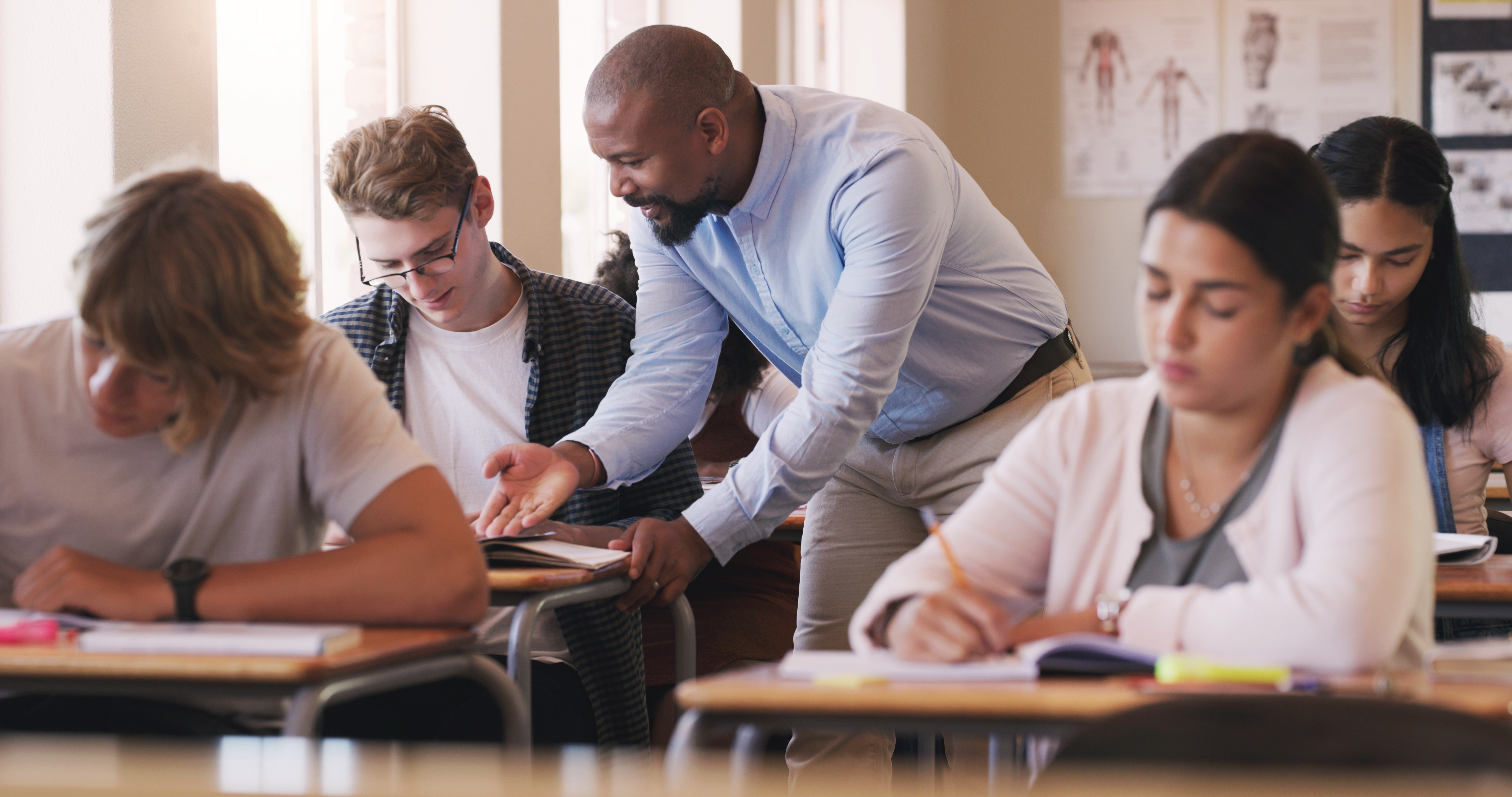 Teacher helping a student at his desk in a classroom